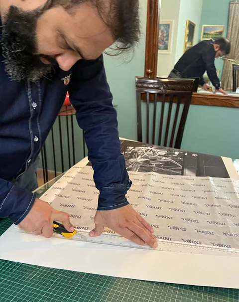 A print being trimmed with a blade along a ruler, under Inked tissue paper