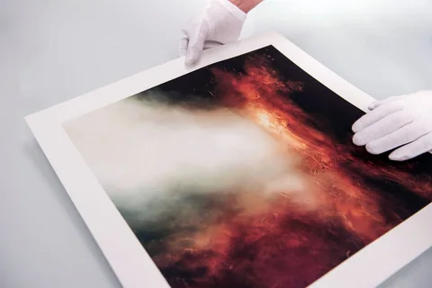 Gloved hands holding a fine art print with a wide white border